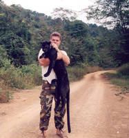 Dr. Lon Grassman holding a collared black leopard in Thailand.